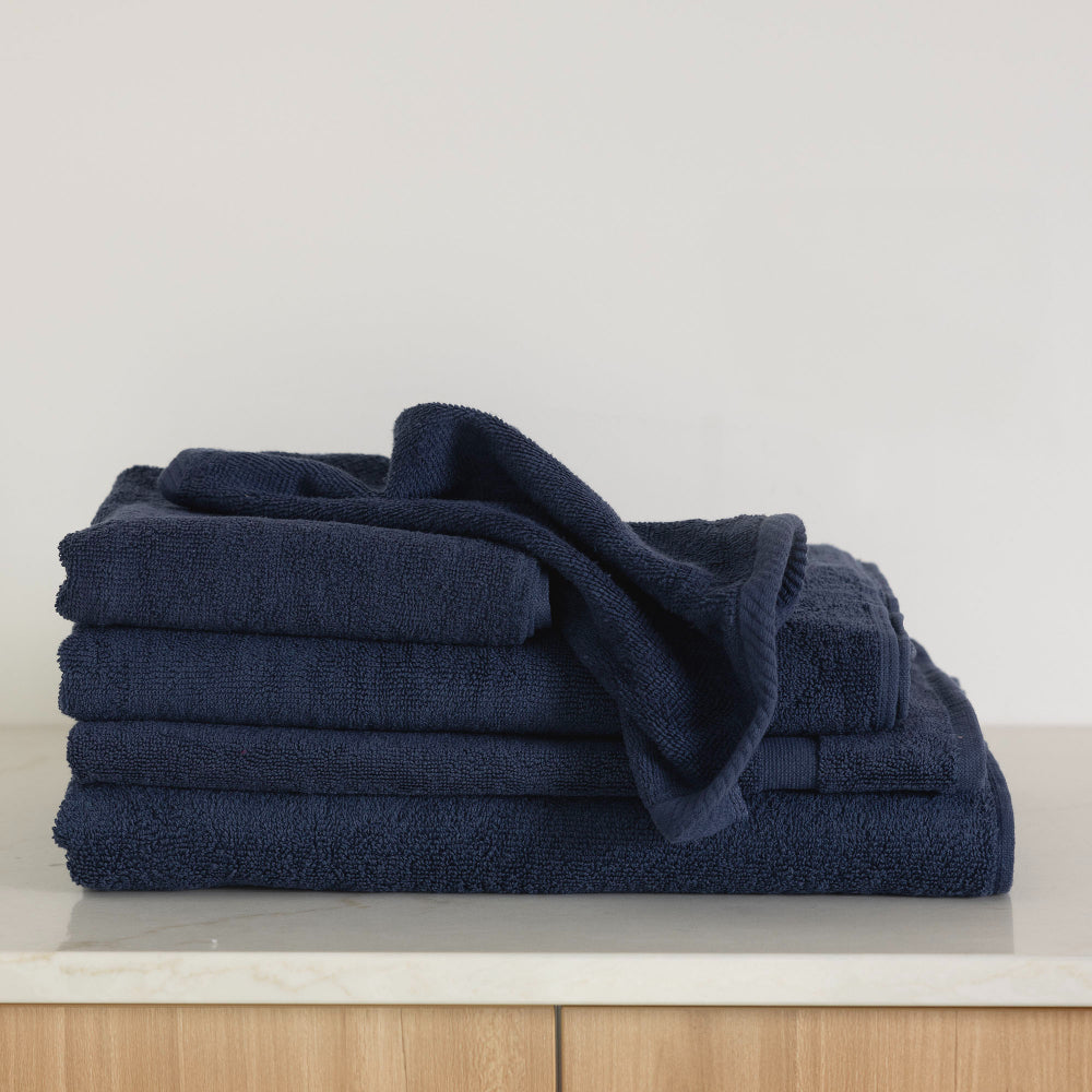 The navy Bambury Chateau bath range folded including the bath sheet, bath towel, bath mat, hand towel, and face washer.