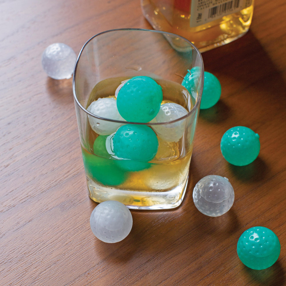 Glass of alcohol with the Kikkerland Golf ball ice cube moulds in and around the drink.