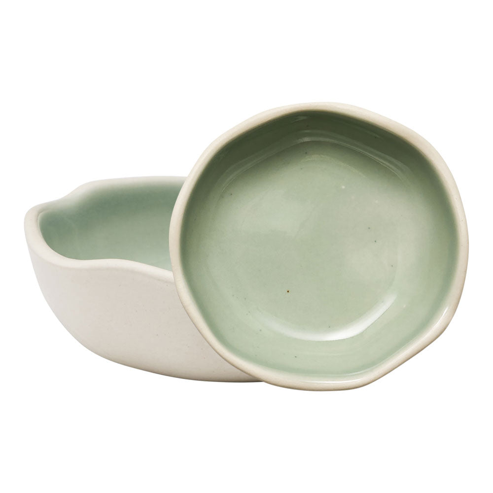 The Ecology Selvedge set of 2 dip bowls featuring a curved edge with the cream exterior and a glossy green interior finish.