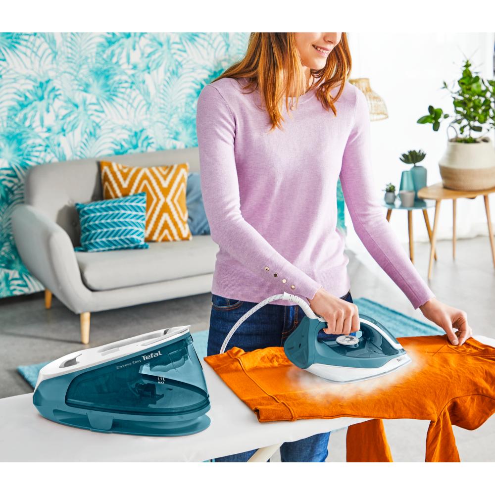 woman using steam iron on orange jumper - House