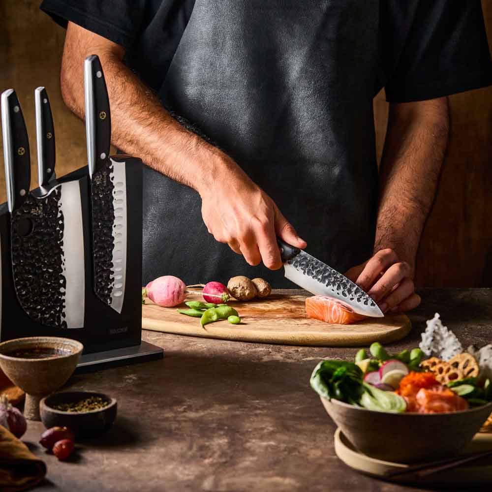 Man slicing salmon with Baccarat KUROI KIBA 7 Piece Knife Block at House