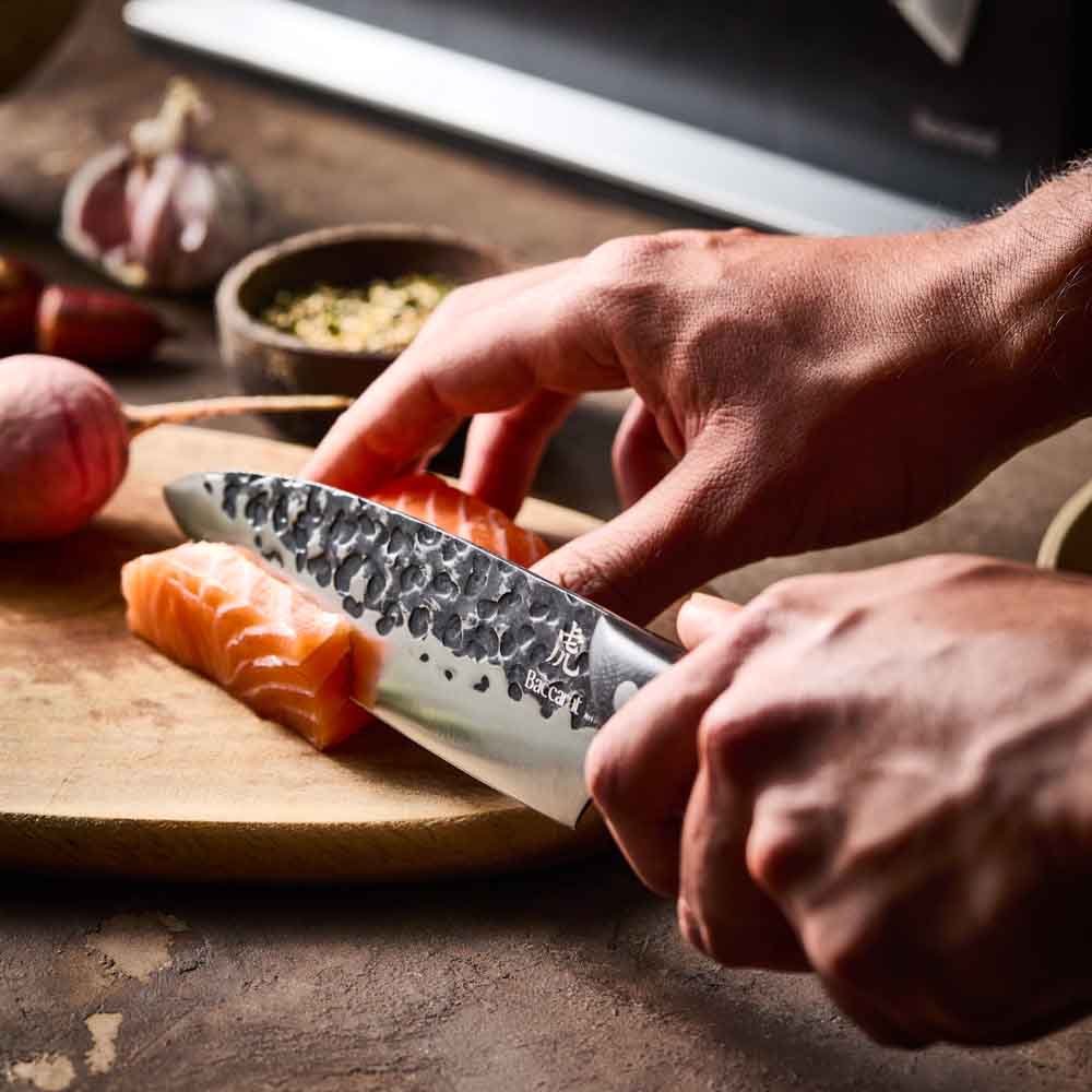 Man slicing salmon with Baccarat KUROI KIBA 7 Piece Knife Block at House