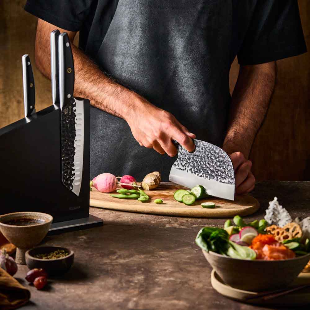 Man slicing cucumber with Baccarat KUROI KIBA 7 Piece Knife Block at House