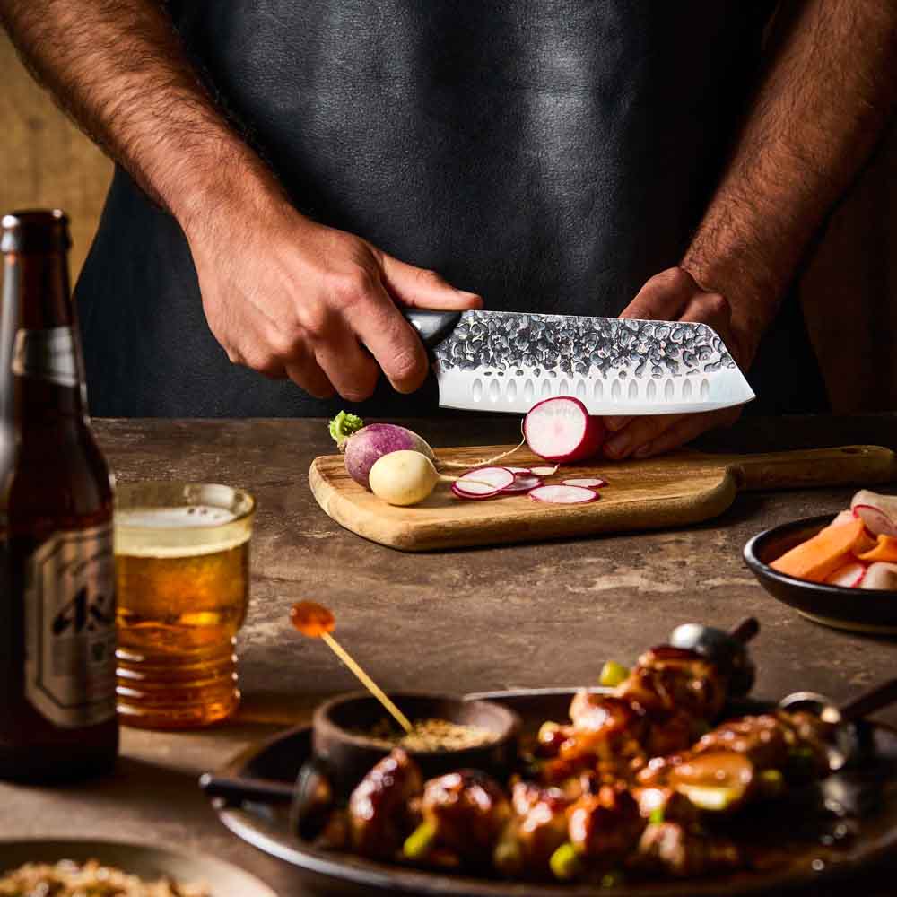 Man slicing radish with Baccarat KUROI KIBA Santoku Knife 18cm at House