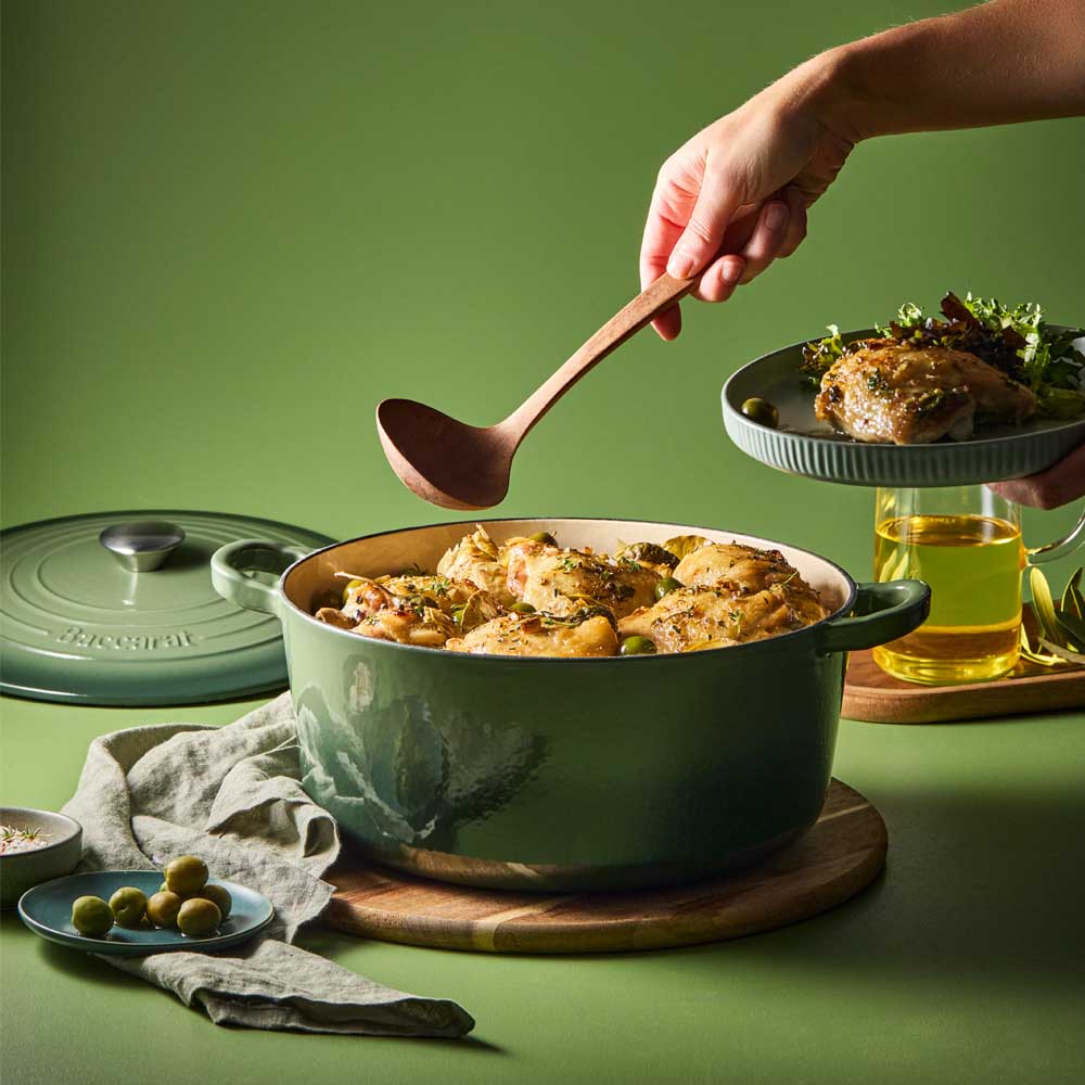woman scooping chicken casserole out of green dutch oven  - House
