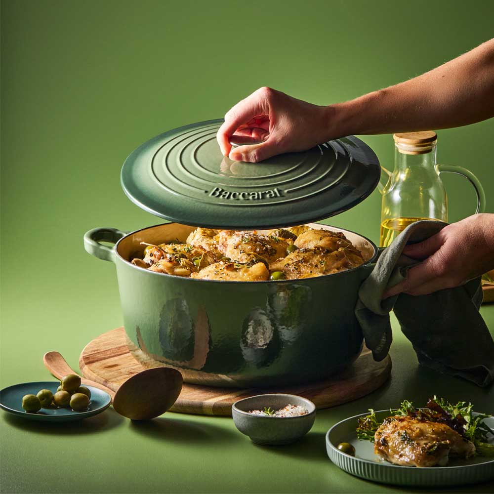 woman lifting lid on green dutch oven with chicken casserole - House