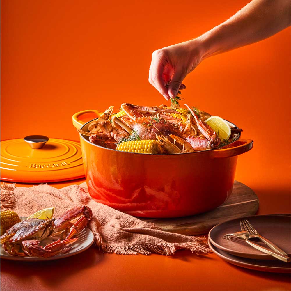 woman sprinkling dill onto seafood casserole in orange dutch oven -House
