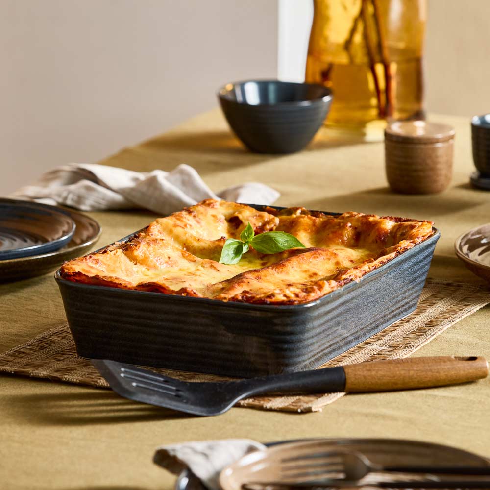 baked lasagne in navy lasagne dish sitting a table - House