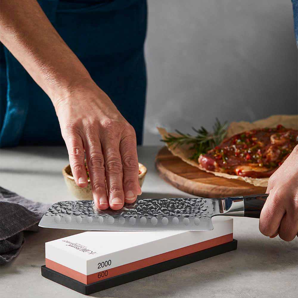 woman sharpening knife using a whetstone - House