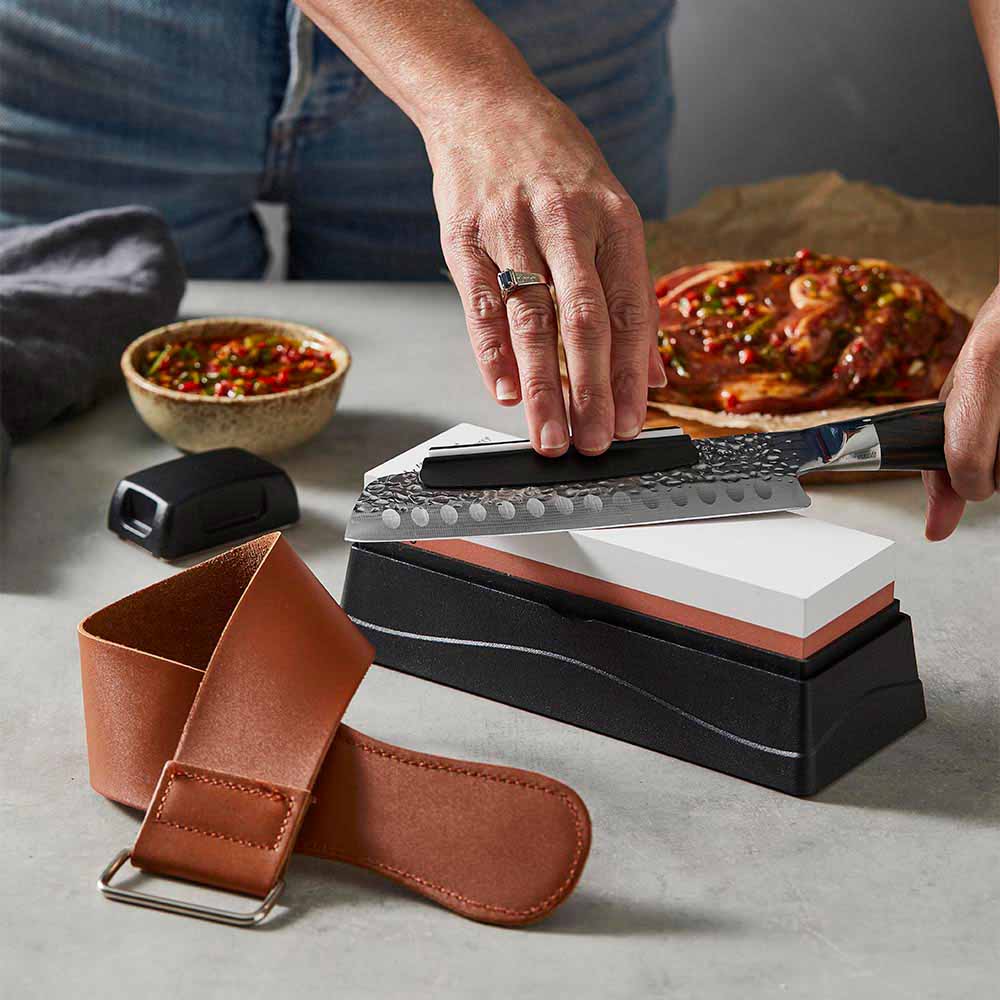 Woman sharpening knife with a whetstone - House