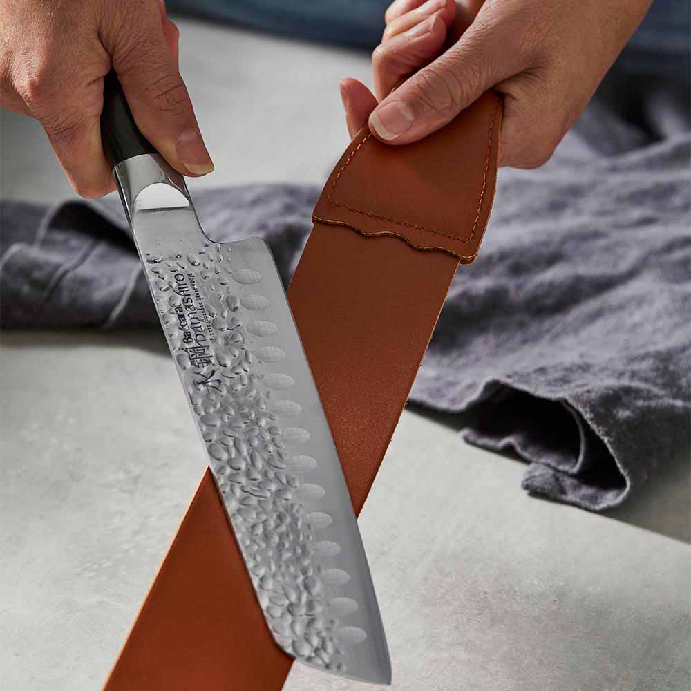 woman polishing knife with leather strop - House