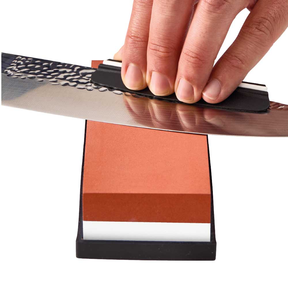 Man sharpening knife with whetstone - House