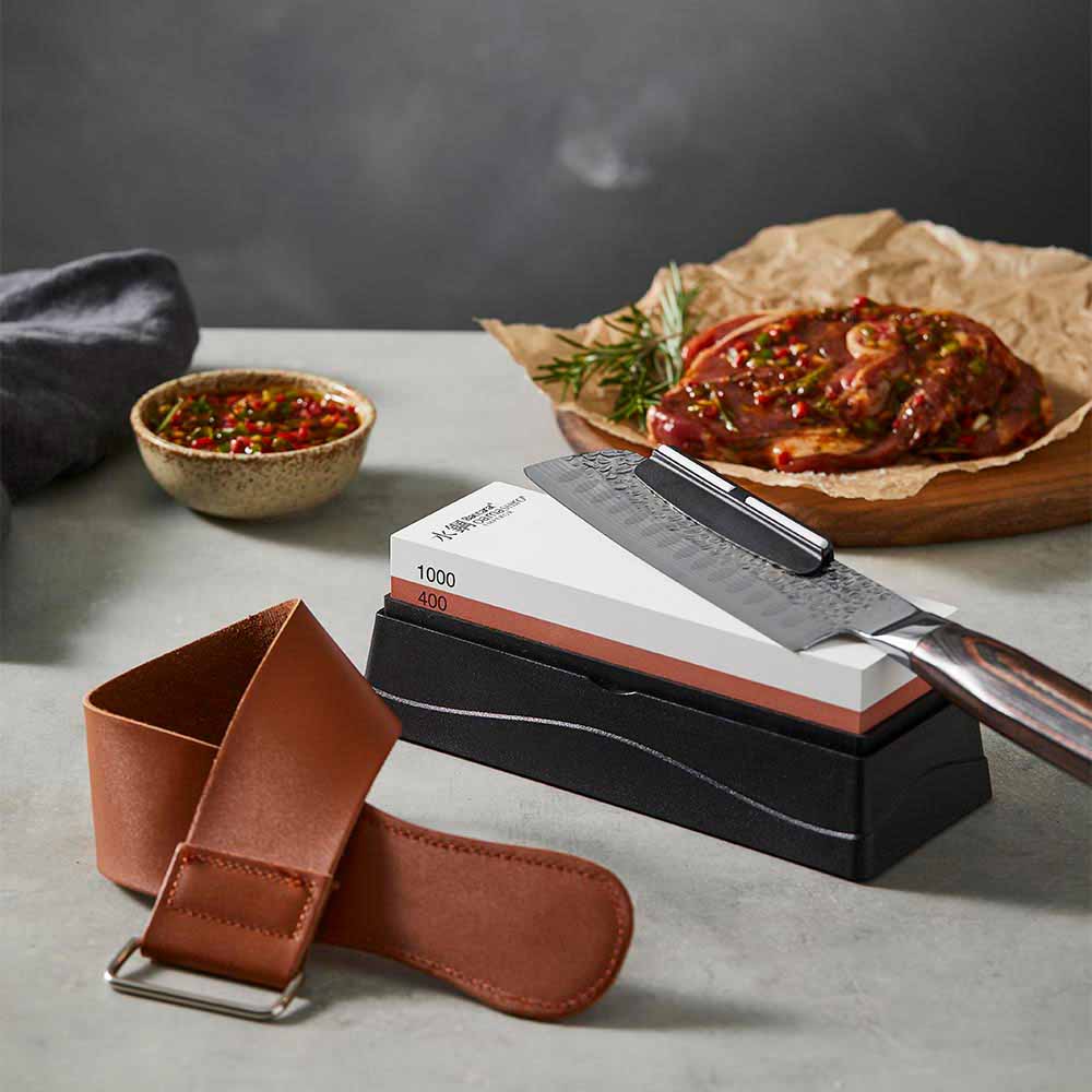 santoku knife sitting on a whetstone with leather strop - House