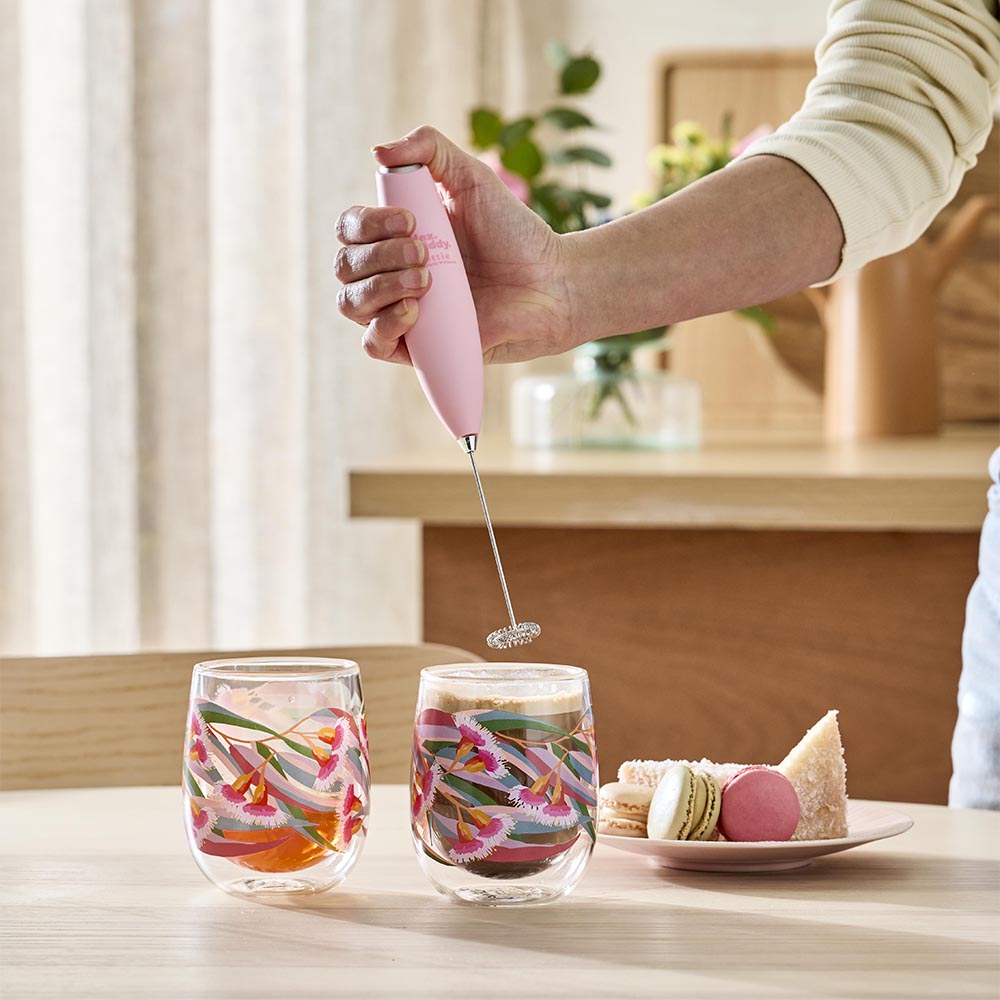 woman holding a pink milk frother to make coffee