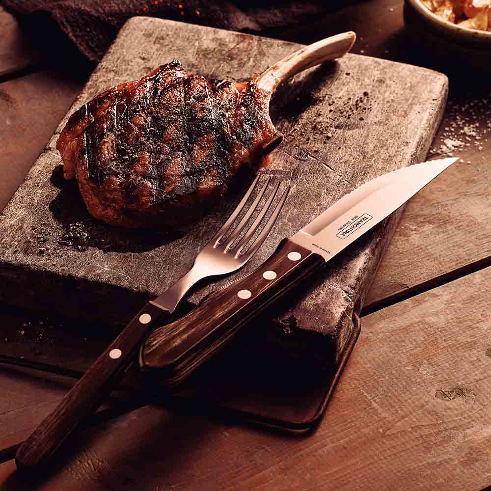 steak knife and fork set with side of steak on wooden board - House