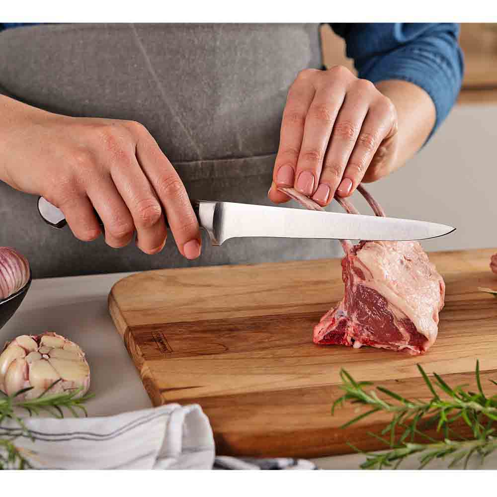 woman frenching rack of lamb with boning knife - House