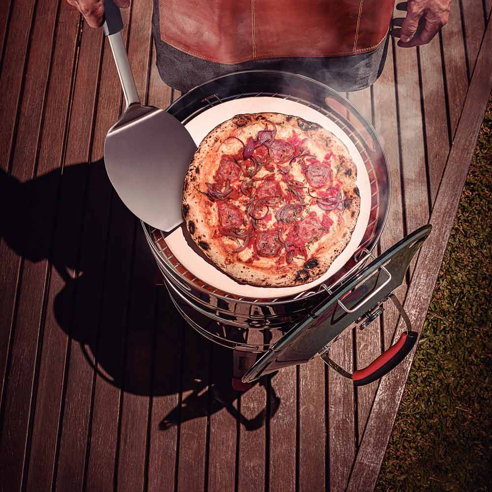 Man cooking pizza on bbq with pizza spatula - House