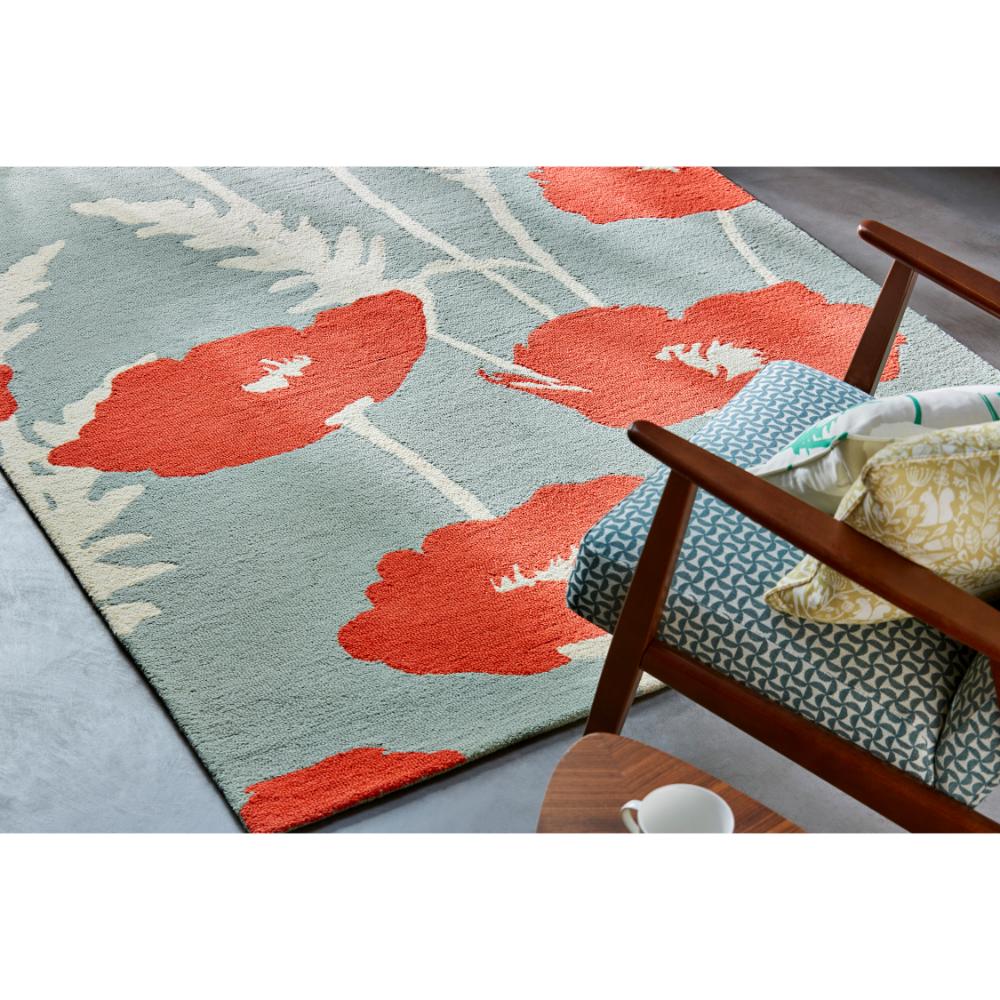 sage wool rug with red poppies next to armchair - House