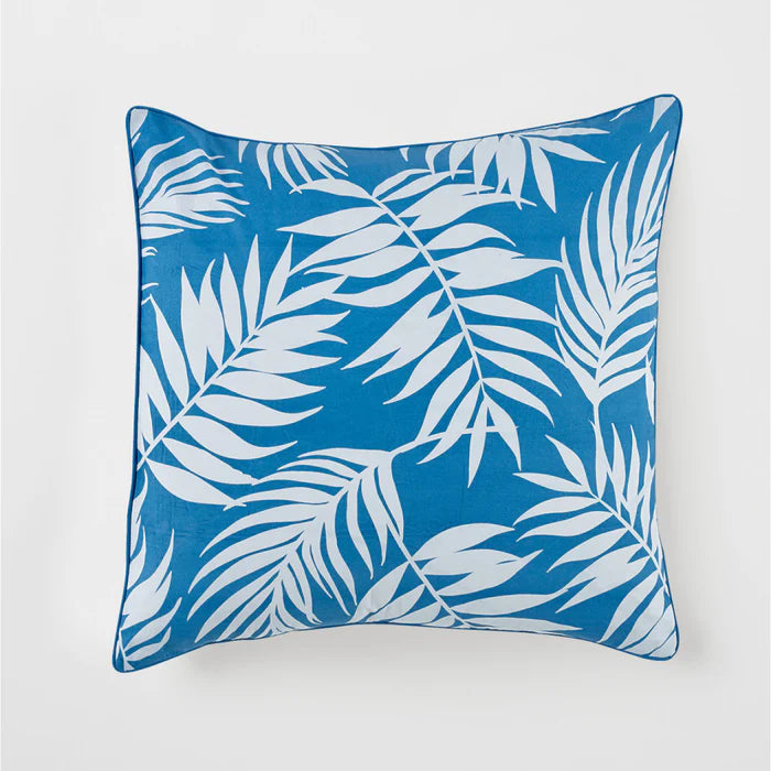 Blue pillow with white leaf pattern on a light gray background