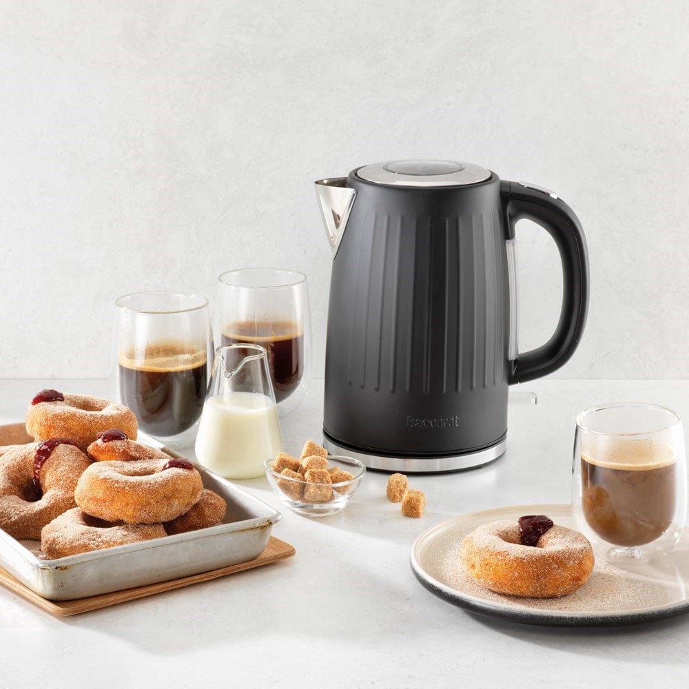 Baccarat The Boiling Point Kettle in Black at House. Black kettle with a display of coffee and donuts.