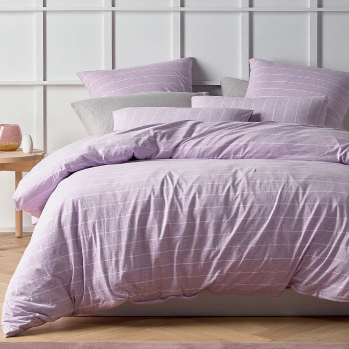 Purple checkered bedding set on a bed with a light gray wall in the background.