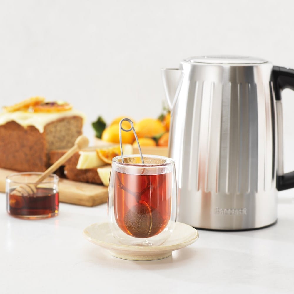 Baccarat The Boiling Point Kettle in Silver at House. Silver kettle with Tea steeping in a double walled glass cup.